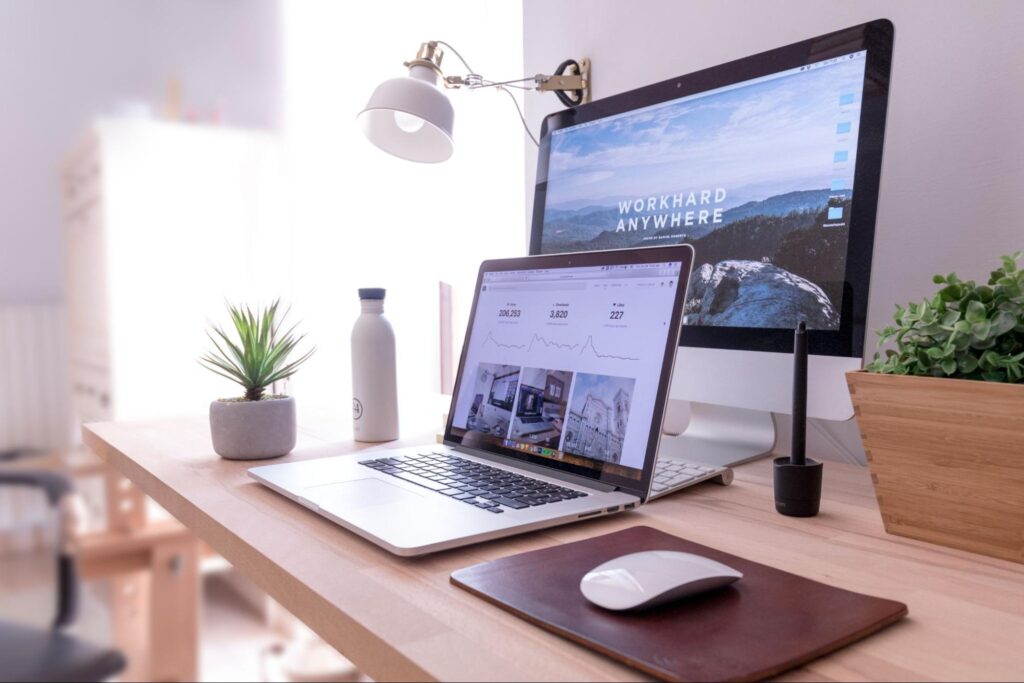 Apple laptop and desktop on wood desk.